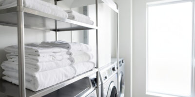 Freshly washed white hotel linens and towels in a commercial laundry, representing hotel linen wash cycles and durability.