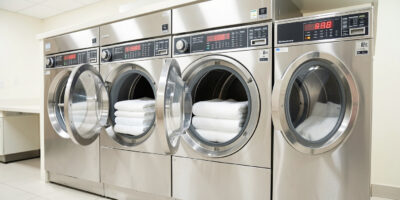 Commercial hotel laundry machines washing white sheets and towels at 60°C during hotel linen washing process