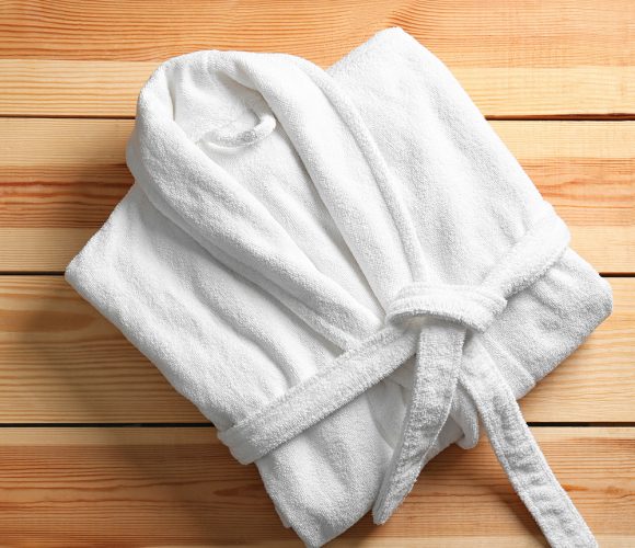 White bathrobe neatly folded on wood